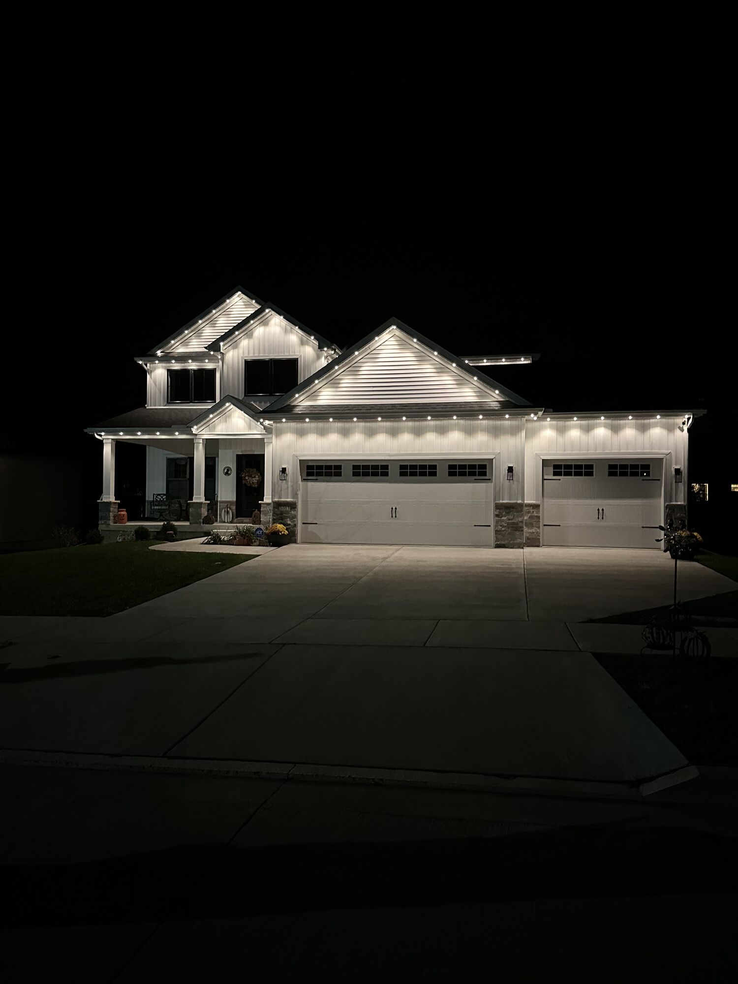 The same white home lit in clean bright white along the rooflines and garage