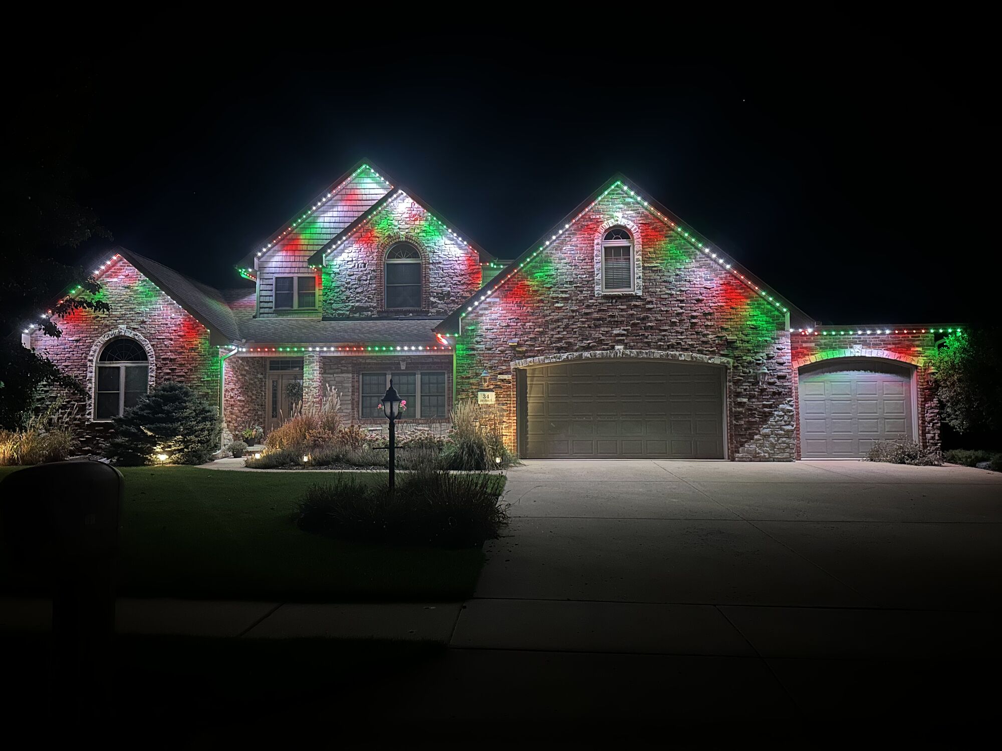 Stone and brick home with alternating red, green and white lights along every gable