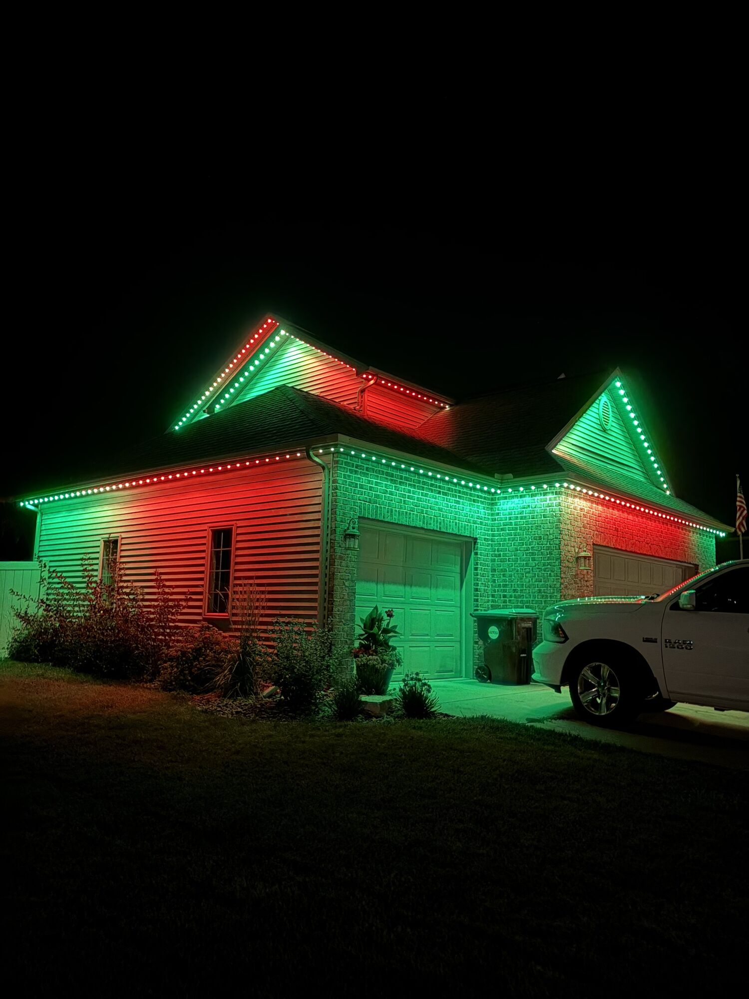 Ranch home washed in red and green holiday lighting along its roofline